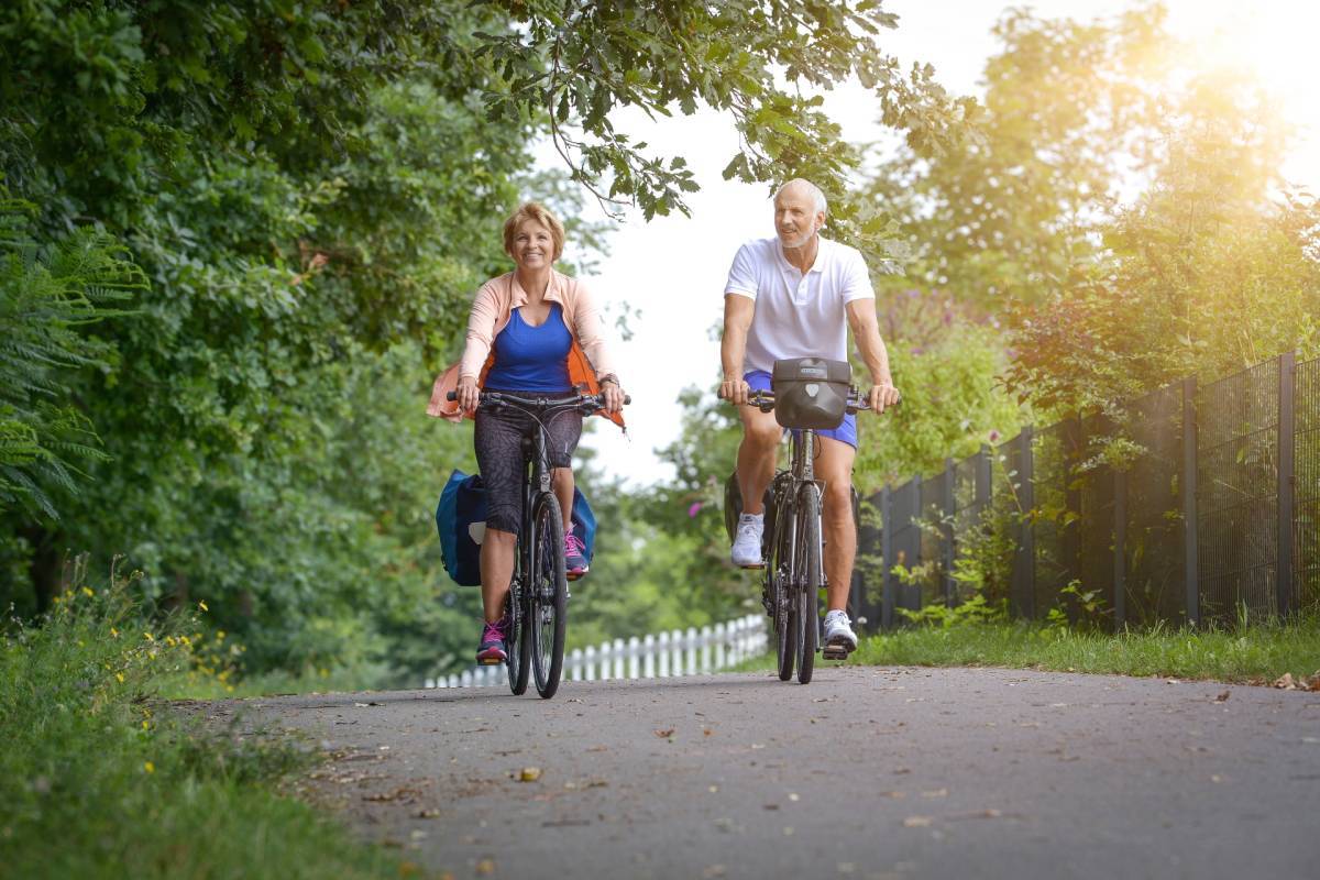 eine Frau und ein Mann fahren mit dem Fahrrad durch die Natur