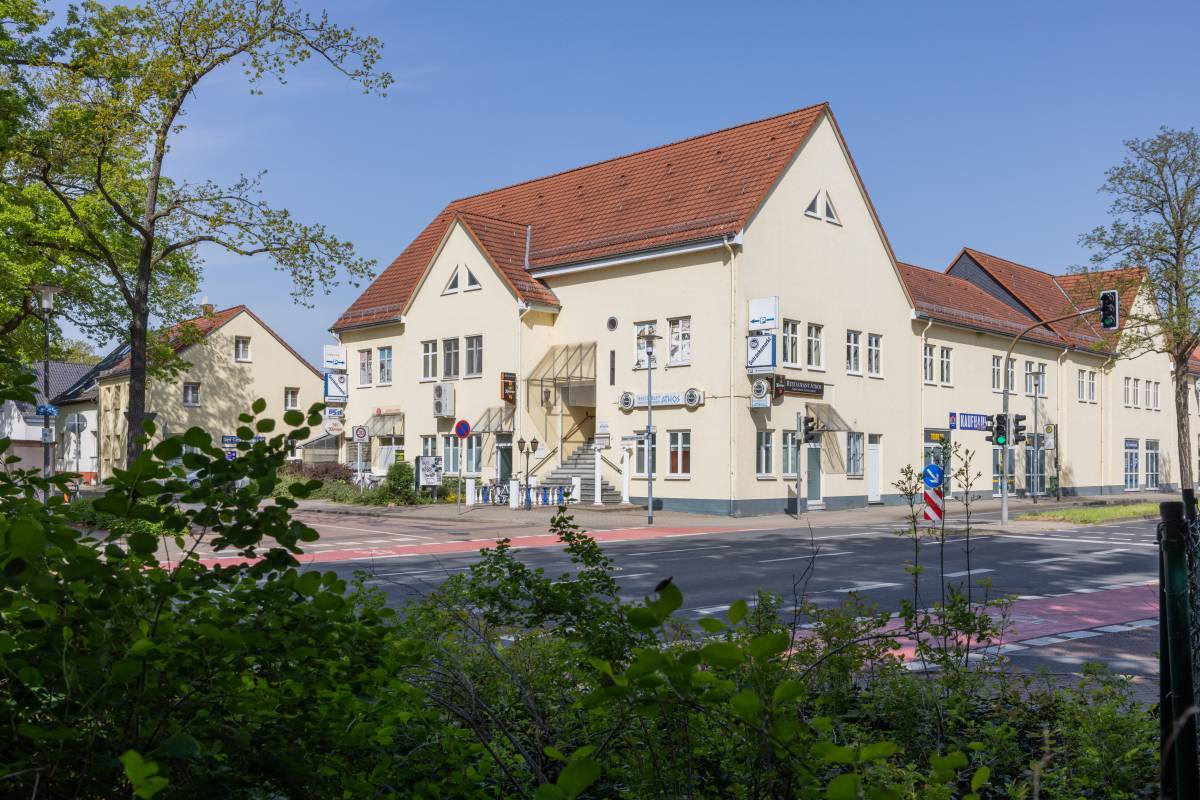Begrünte Sicht auf das Gebäude des Athos Restaurant Dessau mit Treppenaufstieg zum Eingang direkt an der Straße.