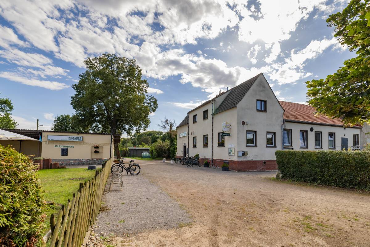 Begr&uuml;nter Au&szlig;enbereich des Restaurant Riekchen Dessau mit Kieselsteinweg und Fahrradstellpl&auml;tzen.