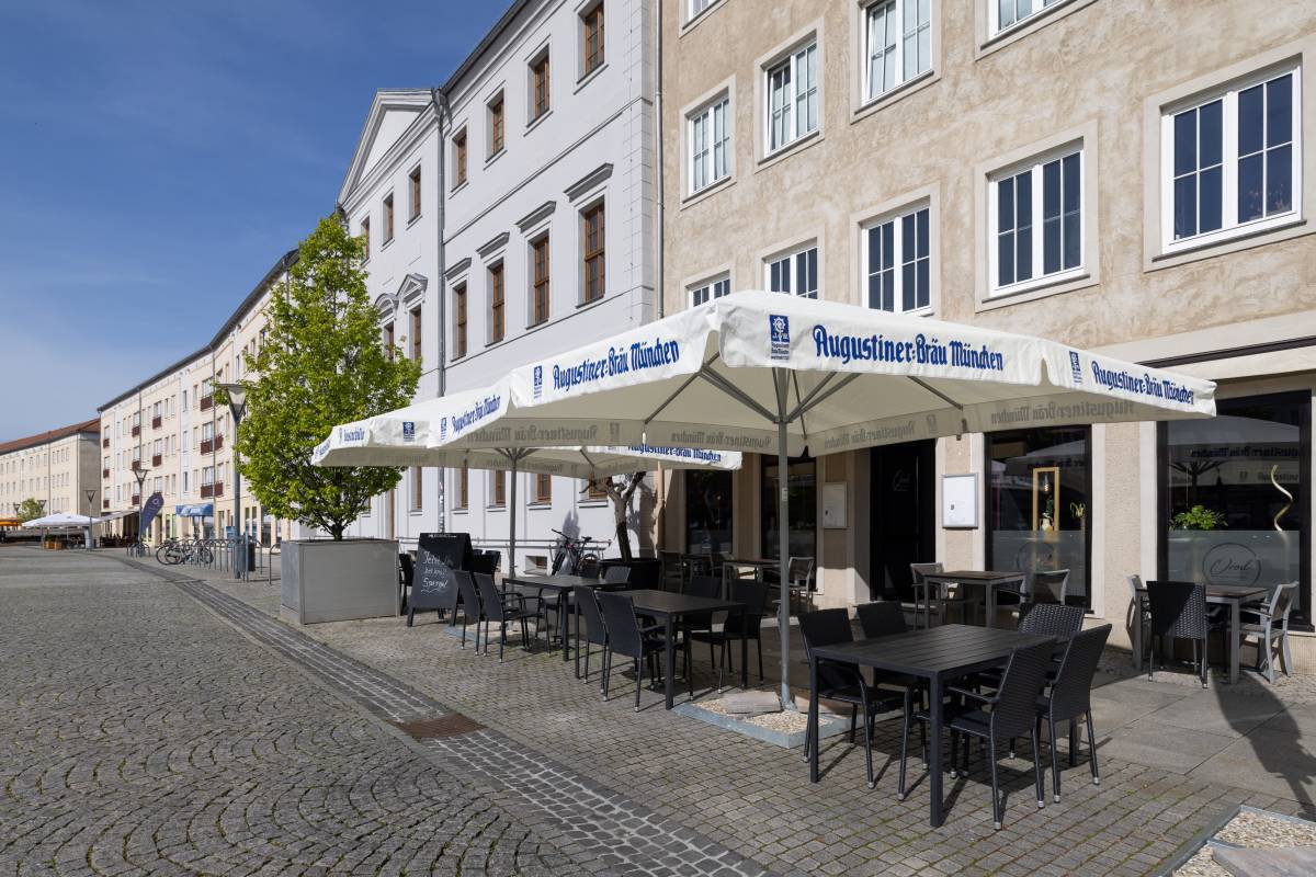 Beschirmter Außensitz-und Essbereich mit seitlicher Bepflanzung des Orod Grillrestaurant Dessau.