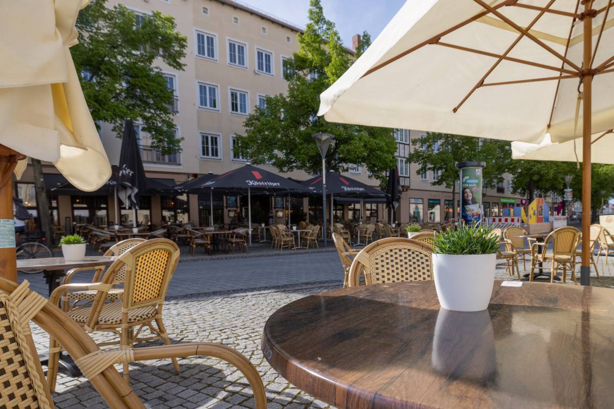Begr&uuml;nter Au&szlig;enbereich mit gem&uuml;tlicher Sitz-und Essgelegenheit mit Sicht auf das Erste Dessauer Kartoffelhaus aus der Entfernung.