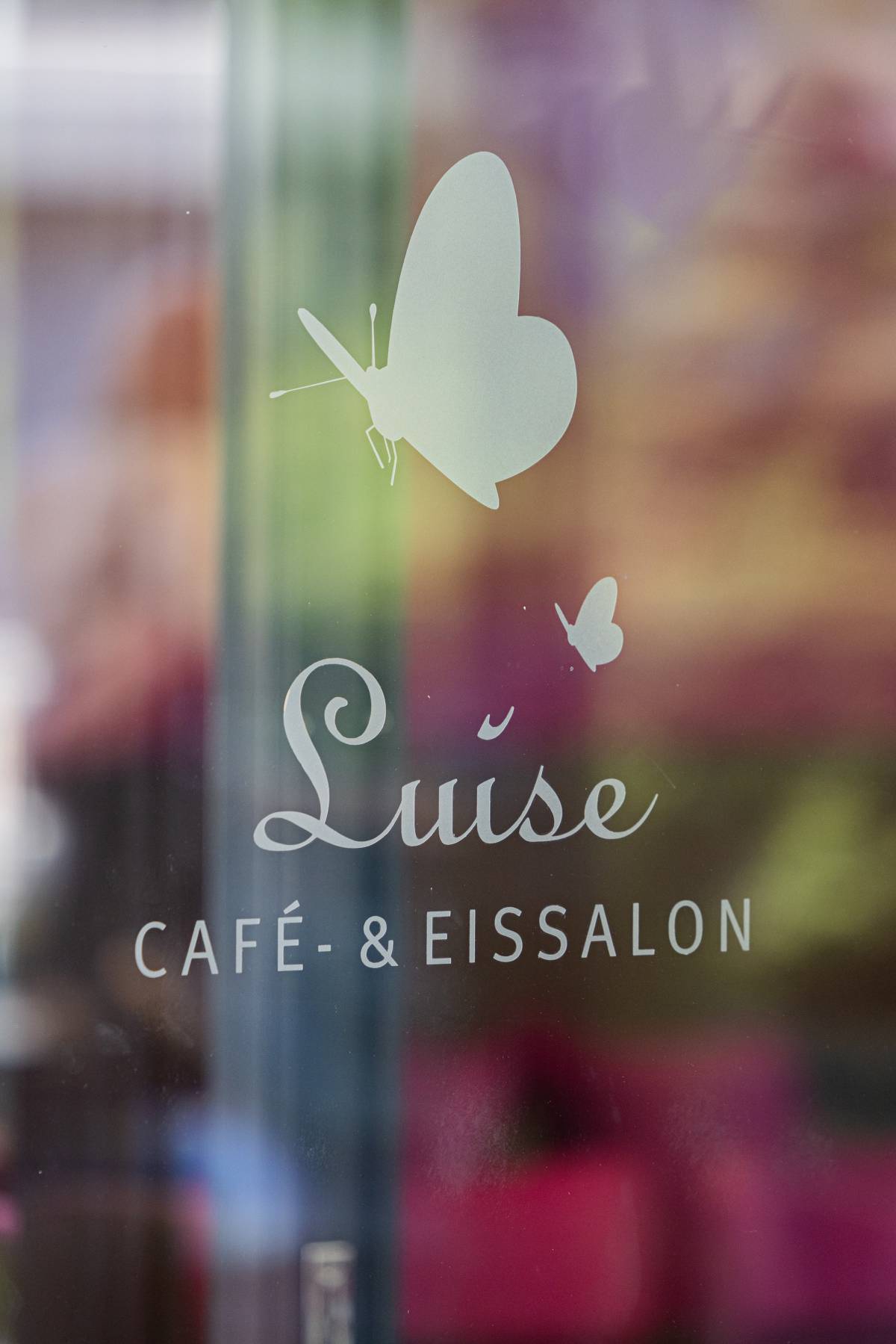 Detailaufnahme des Fensterlogos von dem Eiscafé Luise Dessau mit Schmetterlingsverzierung.