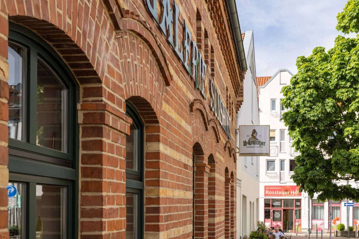 Sicht auf die gr&uuml;nen Rundt&uuml;ren im Eingangsbereich der Galerie Sunshine Dessau mit geziegelter Fassade.