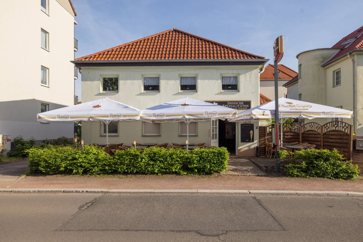 Begrünte Sicht auf den Eingangsbereich des Goa Restaurant in Dessau mit Sonnenbeschirmung und Sitzgelegenheiten.