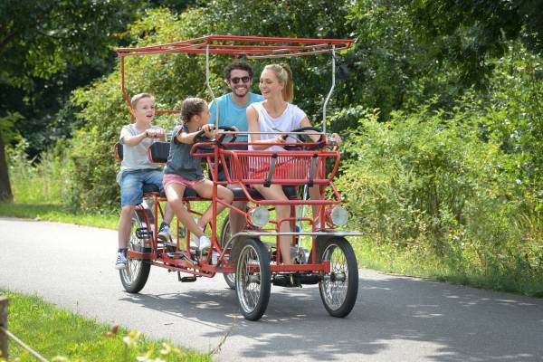 Eltern und zwei Kinder auf einem Tretmobil