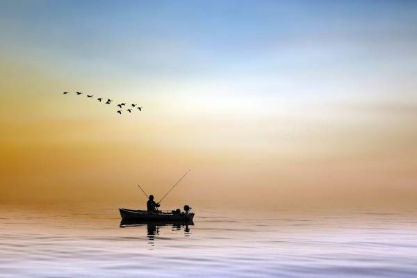 Boot mit Angler auf einem See im Sonnenuntergang