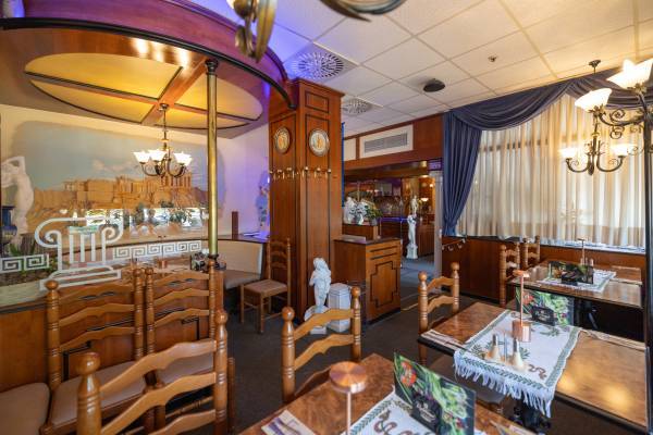 Innensitz- und Essbereich des El Greco Restaurant im rustikalen Stil und dekorativem Tischgedeck.