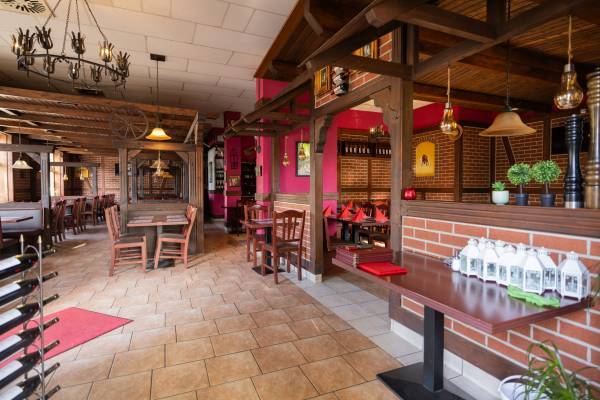 Innensitz- und Essbereich des Restaurant Asado im rustikalen Stil mit roter Wand und Holzbalken